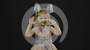 Happy beautiful little baby girl in glossy dress. Christmas. Make faces, dance