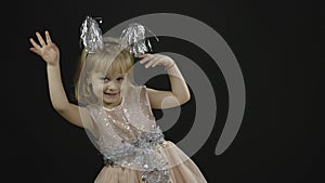 Happy beautiful little baby girl in glossy dress. Christmas. Make faces, dance