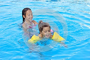 Happy beautiful  little girls swimming in outdoor pool at sunset