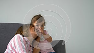 Happy beautiful loving family young mother and daughter laughing sitting on the couch, smiling mom with child having fun enjoy