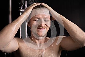 Happy beautiful man taking shower, young smiling guy enjoying showering