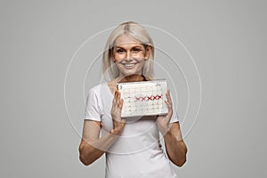 Happy beautiful mature woman holding menstruation calendar and smiling
