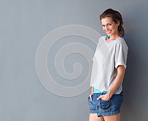 Happy beautiful mid adult woman smiling against gray background