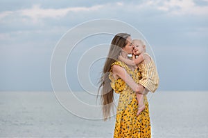 Happy beautiful mother huges baby near the sea. Mother and daughter