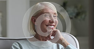 Happy beautiful older woman looking away at camera at home