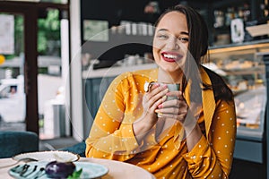 Happy beautiful plus size woman smiling and drinking coffee in cafe