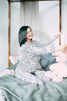 Happy beautiful pregnant caucasian woman with big belly in pajamas in the bedroom, future parrents, waiting for a child