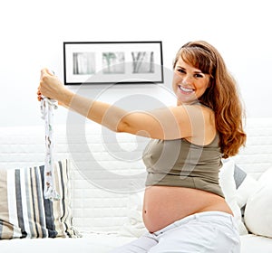 Happy beautiful pregnant woman with baby clothes