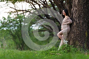 Happy beautiful pregnant woman stroking her belly in the park