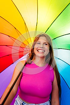 Happy beautiful pretty smiling young teen girl wearing bright pink top at colourful rainbow background