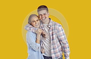 Studio portrait of cheerful siblings or teen couple hugging each other and smiling