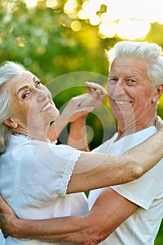 Happy beautiful senior couple dancing in summer park