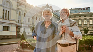 Happy and beautiful senior couple holding hands and smiling while standing outdoors together