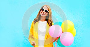 Happy beautiful smiling woman holds an air balloons in yellow coat