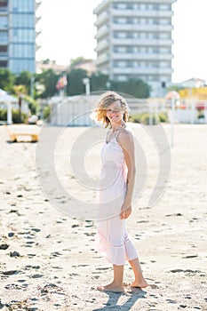 Happy beautiful smiling young woman walk at the sand beach, looking at camera