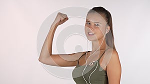 Happy beautiful sportswoman showing her biceps, pointing to the camera at you