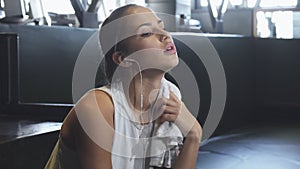 Happy beautiful sportswoman smiling to the camera wiping sweat off her neck at the gym