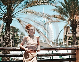 Happy beautiful tourist woman in summer dress enjoying vacation in Dubai in United Arab Emirates