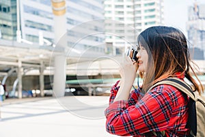 Happy beautiful traveler asian woman carry backpack. Young joyful asian women using camera to making photo during city tour.