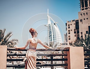 Happy beautiful unrecognizable tourist woman in summer dress enjoying hotel Burj al Arab in Dubai in United Arab