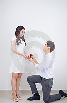 Happy beautiful Vietnamese girl looking at her boyfriend and smiling while getting a marriage proposal