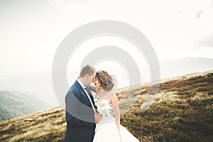 Happy beautiful wedding couple bride and groom at wedding day outdoors on the mountains rock. Happy marriage couple