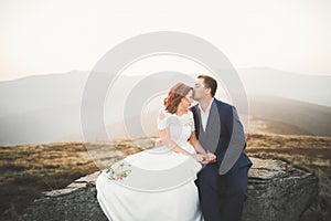 Happy beautiful wedding couple bride and groom at wedding day outdoors on the mountains rock. Happy marriage couple