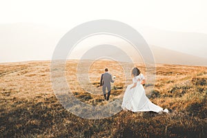 Happy beautiful wedding couple bride and groom at wedding day outdoors on the mountains rock. Happy marriage couple