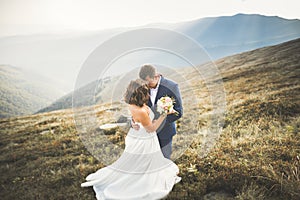 Happy beautiful wedding couple bride and groom at wedding day outdoors on the mountains rock. Happy marriage couple