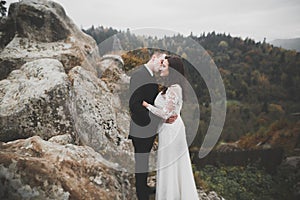 Happy beautiful wedding couple bride and groom at wedding day outdoors on the mountains rock. Happy marriage couple