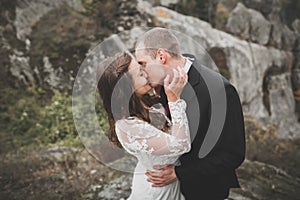 Happy beautiful wedding couple bride and groom at wedding day outdoors on the mountains rock. Happy marriage couple