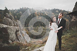 Happy beautiful wedding couple bride and groom at wedding day outdoors on the mountains rock. Happy marriage couple