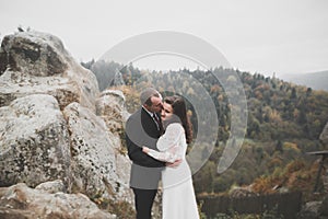 Happy beautiful wedding couple bride and groom at wedding day outdoors on the mountains rock. Happy marriage couple