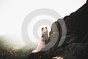 Happy beautiful wedding couple bride and groom at wedding day outdoors on the mountains rock. Happy marriage couple