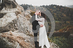 Happy beautiful wedding couple bride and groom at wedding day outdoors on the mountains rock. Happy marriage couple