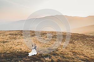 Happy beautiful wedding couple bride and groom at wedding day outdoors on the mountains rock. Happy marriage couple