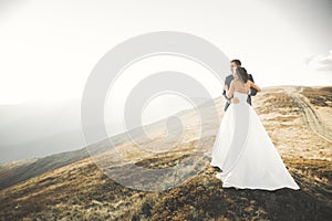 Happy beautiful wedding couple bride and groom at wedding day outdoors on the mountains rock. Happy marriage couple