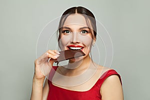 Happy beautiful woman biting chocolate, cheat meal and diet concept