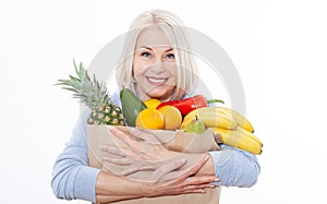 Happy beautiful woman with blond hair holds many fruits oranges, lemon, bananas, kiwi, avocado, pears and pineapple in her hands