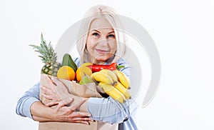 Happy beautiful woman with blond hair holds many fruits oranges, lemon, bananas, kiwi, avocado, pears and pineapple in her hands