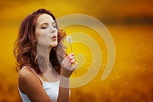 Happy beautiful woman blowing dandelion