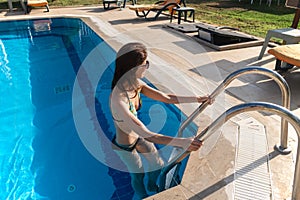 Happy beautiful woman coming out from swimming pool