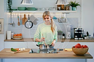 Happy beautiful woman cooking healthy food in casserole in the kitchen at home