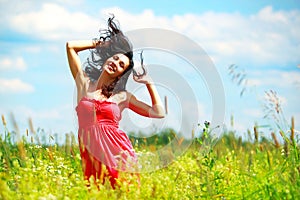 Happy beautiful woman dancing in meadow