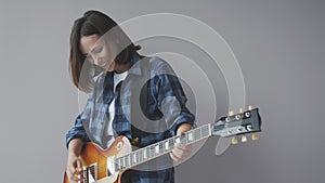 Happy beautiful woman with electric guitar plays rock and blues song wearing blue casual shirt smiling and laughing. Rock guitar p