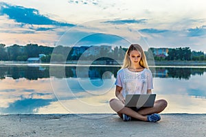 Happy beautiful woman, girl with laptop surfing the web near by lake