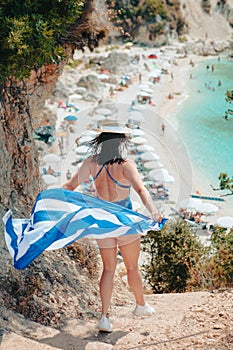 happy beautiful woman with greece flag running to the sea beach