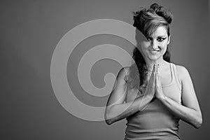 Happy beautiful woman with hair tied and makeup against gray background