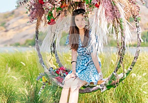 Happy beautiful woman having relax time on a flower swing in nature field for nature hapiness lifestyle