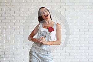 Happy beautiful woman holding near of her heart red paper heart